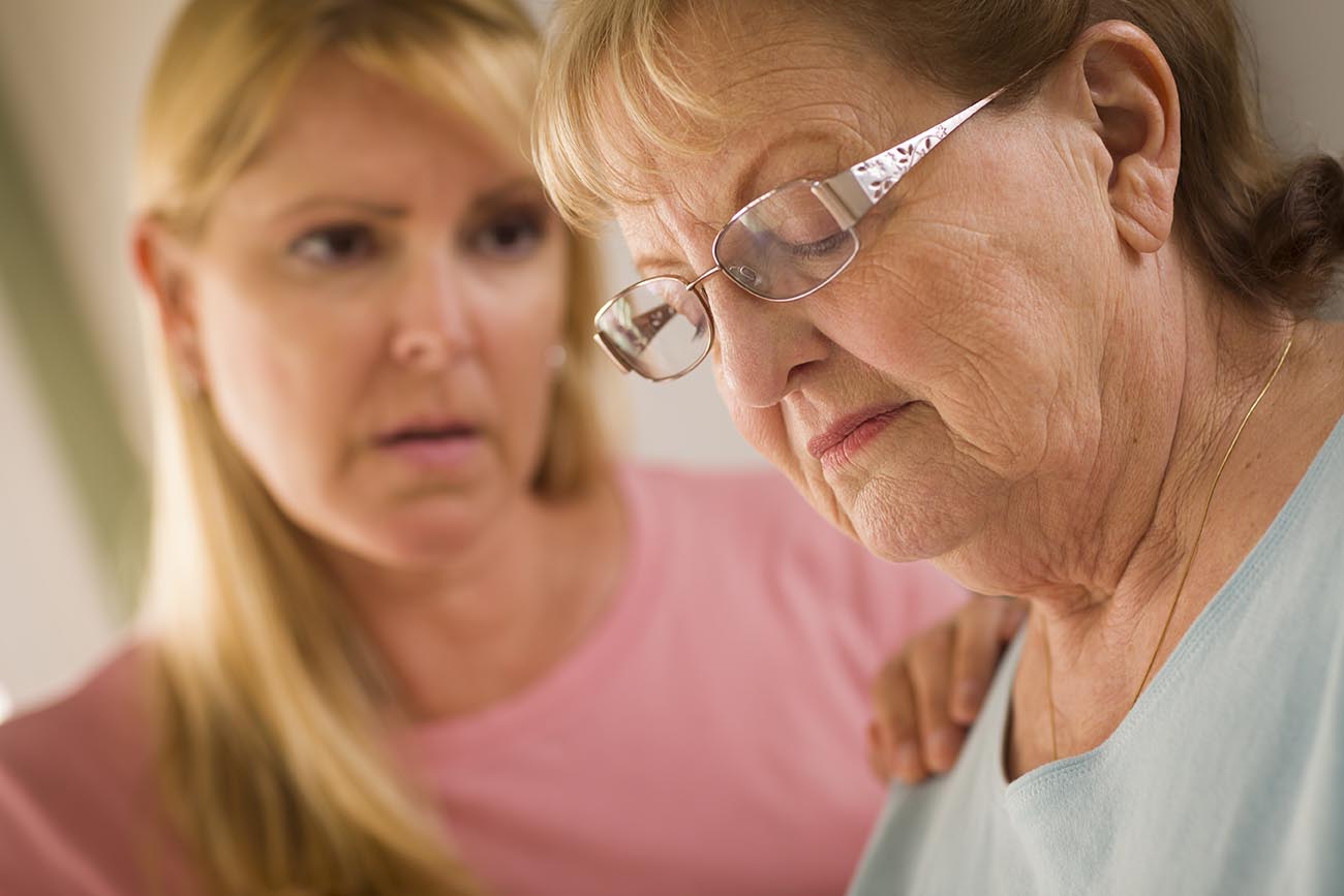 Young Adult Woman Consoles Sad Senior Adult Female.