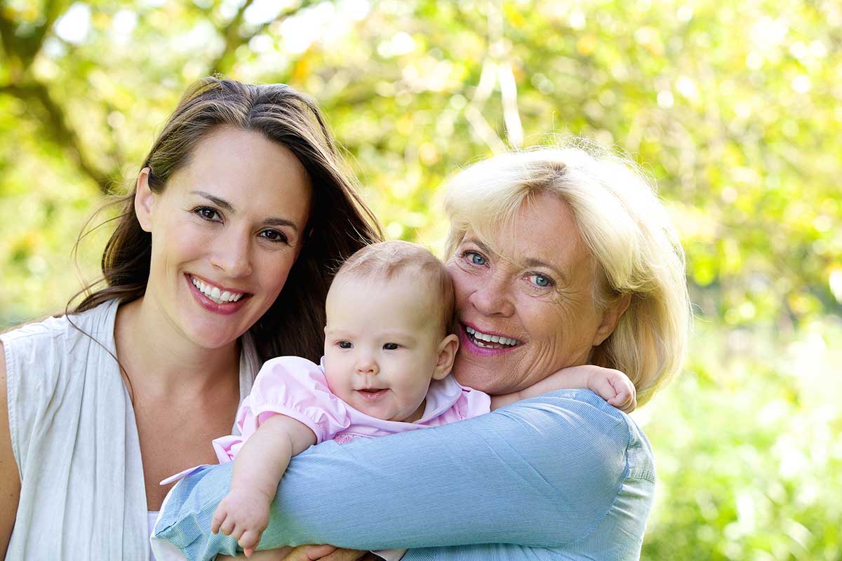 Close up portrait of a grandmother and mother smiling with baby